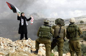 A Palestinian woman stands in front of Israeli soldiers during a protest in the West Bank village of Bilin near Ramallah against Israel's offensive in Gaza January 8, 2009.(REUTERS/Eric Gaillard)